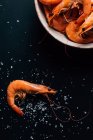Верхний вид плиты с креветками на темном столе с солью — стоковое фото