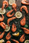 Elevated view of lemon slices, mint leaves and shrimps on table with black pepper and salt — Stock Photo