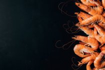 Vista superior da pilha de camarões na mesa escura — Fotografia de Stock