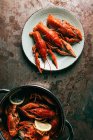 Elevated view of plate and saucepan with crayfishes on rustic table — Stock Photo