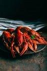 Closeup shot of pile of crayfishes with mint and lemon slices on plate and kitchen towel on table — Stock Photo