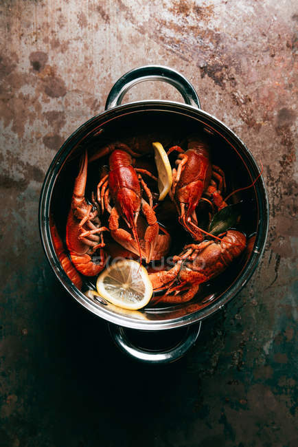 Top view of crayfishes with bay leaf and lemon slices in saucepan — Stock Photo