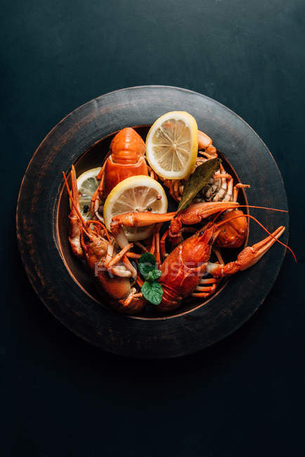 Vista elevada de lagostins com folha de louro, hortelã e fatias de limão no prato — Fotografia de Stock