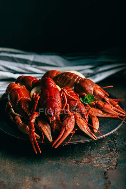 Primer plano de pila de cangrejos de río con rodajas de menta y limón en el plato y toalla de cocina en la mesa - foto de stock
