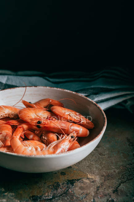 Closeup view of pile of shrimps on plate and kitchen towel on table — Stock Photo