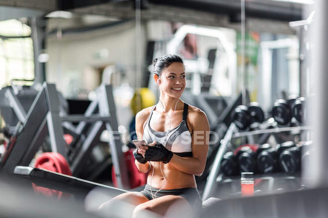 Donna sorridente che ascolta musica in palestra — Foto stock