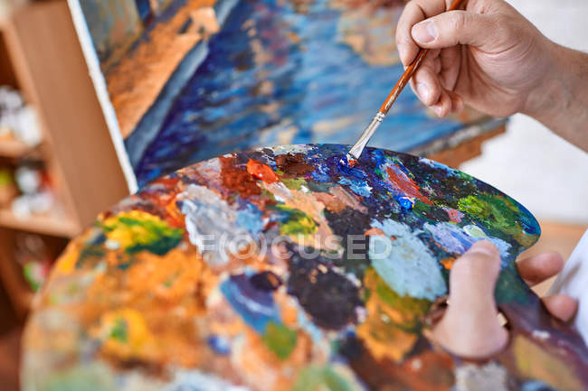 Artist with paintbrush mixing oil paints — Stock Photo