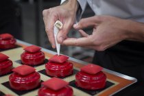 Крупним планом шеф-кухаря, який прикрашає торти з перловими цукерками — стокове фото