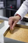 Обрезанный вид руки шеф-повара, проверяющего, приготовлен ли торт — стоковое фото