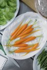 Bebé zanahorias y guarniciones vegetales en la mesa - foto de stock