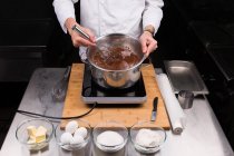 Обрезанный вид, как шеф-повар бросает шоколад в Бейн-Мари — стоковое фото