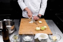 Cropped view of male chef cutting onions — Stock Photo