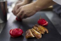 Cropped view of chef preparing fruit garnish for meat — Stock Photo