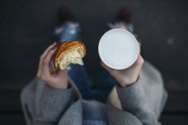 Woman holding croissant and cup of cappuccino — Stock Photo