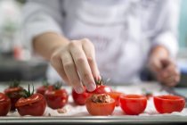 Close-up view of chef hands preparing stuffed tomatoes — Stock Photo