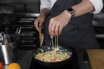 Обрізаний вид чоловічої шеф-кухарки готує макарони — стокове фото