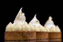 Gâteaux ronds avec décoration crème sur fond noir — Photo de stock