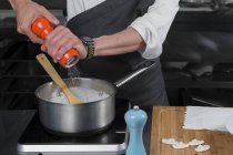 Cropped view of male chef salting cream of mushroom soup in pan — Stock Photo