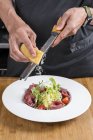 Vista cortada do chef macho ralando queijo na salada — Fotografia de Stock