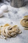 Homemade pasta on kitchen table with eggs — Stock Photo