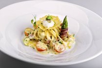 Creamy tagliatelle with bacon, vegetables and poached egg — Stock Photo