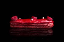Eclair with red glaze and fresh raspberries — Stock Photo