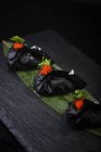 Черные пельмени с икрой на листе — стоковое фото