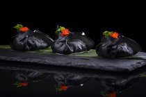 Black dumplings with caviar decoration served on leaf — Stock Photo