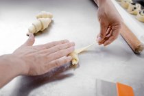 Primo piano di mani di pasticciere che fanno piccoli croissant — Foto stock