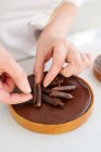 Gros plan sur les mains du chef décorant la tarte au chocolat — Photo de stock
