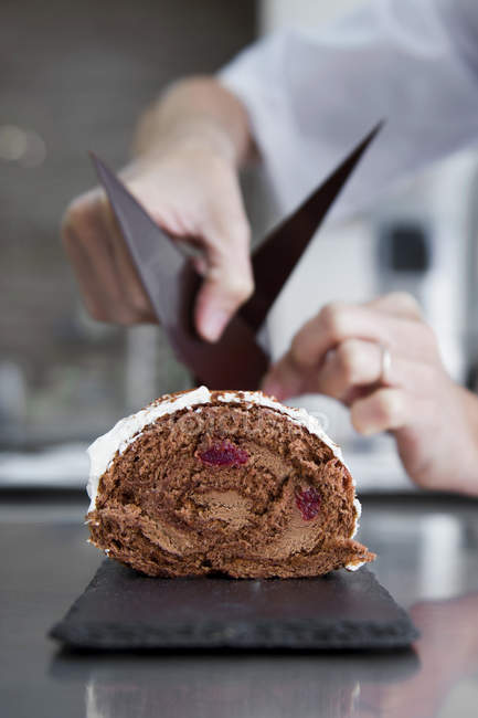 Confectioner preparing chocolate swiss roll — Stock Photo