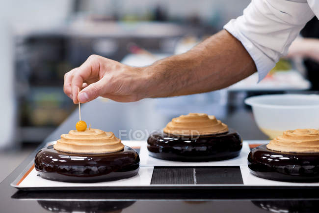 Крупним планом чоловічий шеф-кухар прикрашає торт з вишнею — стокове фото