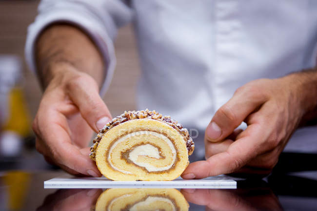 Gros plan du pâtissier masculin tenant un rouleau suisse — Photo de stock
