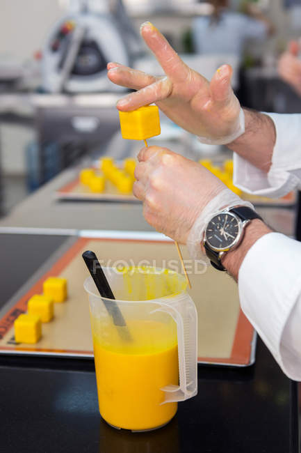 Gros plan du chef décorant les gâteaux avec de la glaçure jaune — Photo de stock