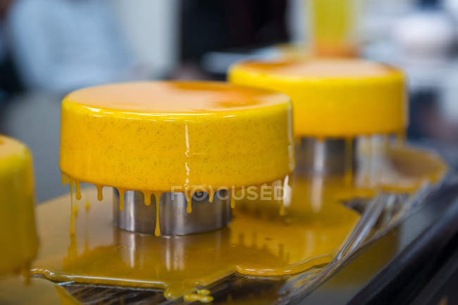 Cakes with yellow dripping glaze presented on stands — Stock Photo