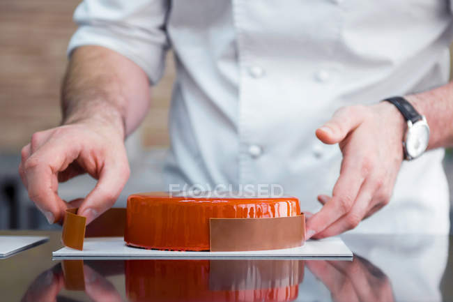Cropped view of chef decorating cake with chocolate border — Stock Photo