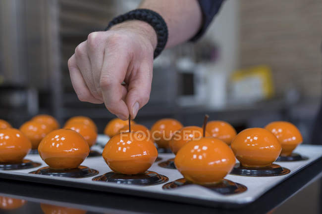 Vista de cerca del confitero haciendo pasteles en forma de fruta - foto de stock