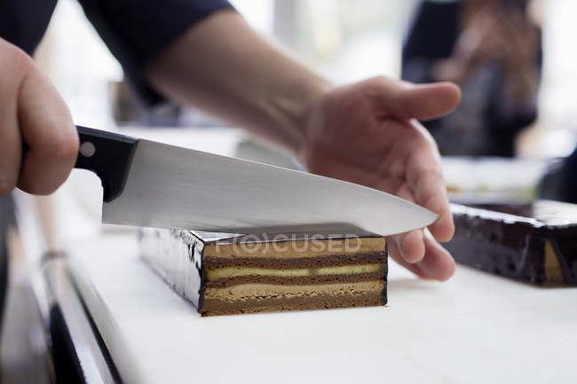 Close-up view of confectioner cutting cake — Stock Photo