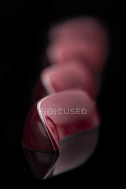 Schokolade mit roter Glasur auf schwarzem Hintergrund — Stockfoto
