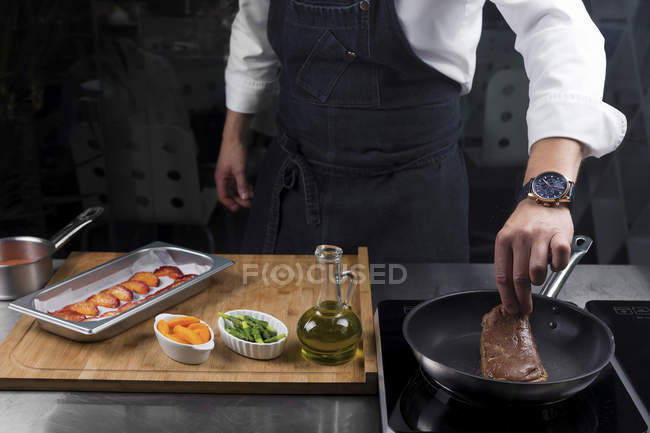 Vista recortada del chef macho asando filete - foto de stock