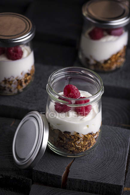 Parfait di yogurt e granola in vasetti sul tavolo — Foto stock