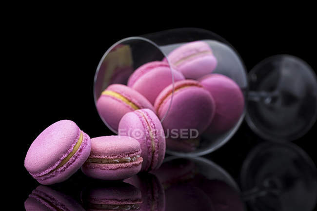Pink macarons in glass vase on black background — Stock Photo