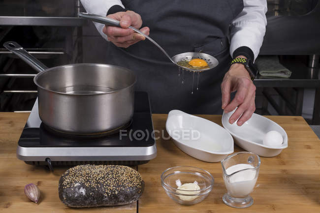 Cropped view of male chef separating yolks from proteins — Stock Photo
