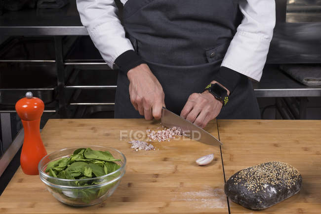 Vista recortada del chef masculino cortando cebolla y jamón - foto de stock
