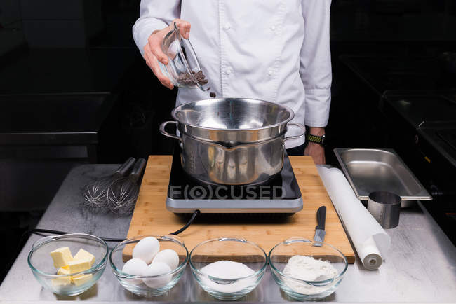 Обрізаний вигляд чоловічого шеф-кухаря, що наливає шоколад у бака-Мері — стокове фото