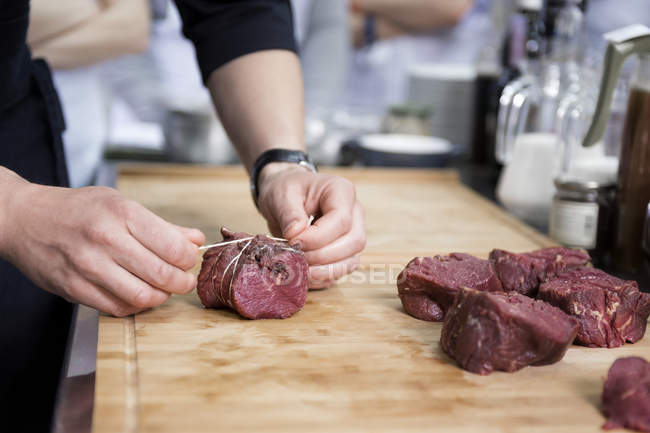 Abgeschnittene Ansicht vom Koch, der Fleischscheiben bindet — Stockfoto