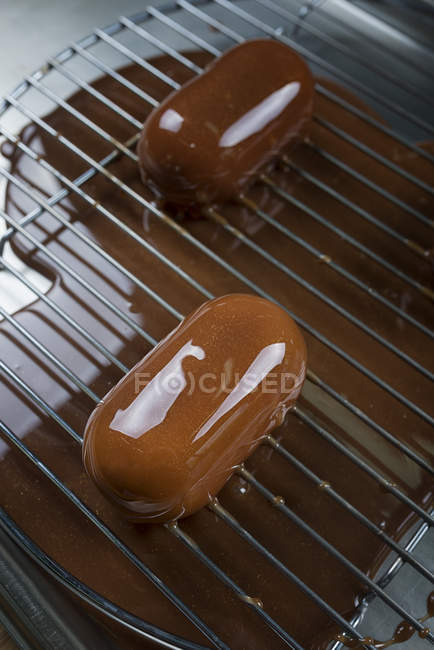 Pasteles recubiertos de esmalte de chocolate en el stand - foto de stock