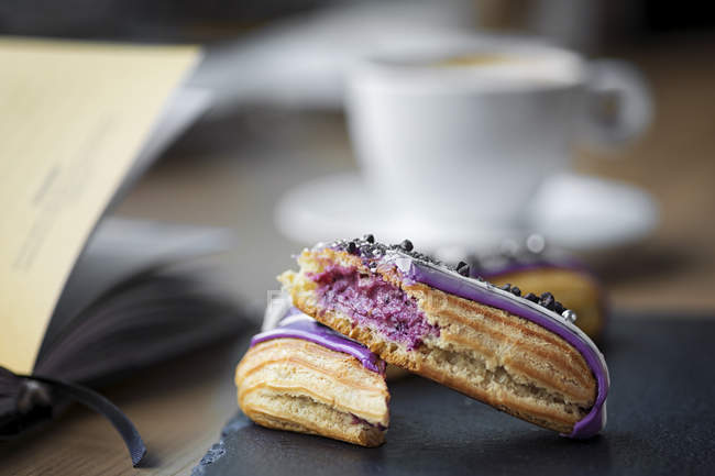 Eclairs with violet cream filling on table — Stock Photo