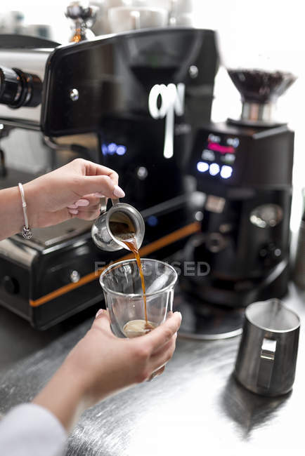 Close-up view of female barista hands pouring espresso — Stock Photo