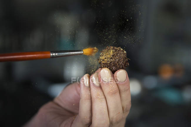 Close-up view of female hand decorating chocolate candy — Stock Photo